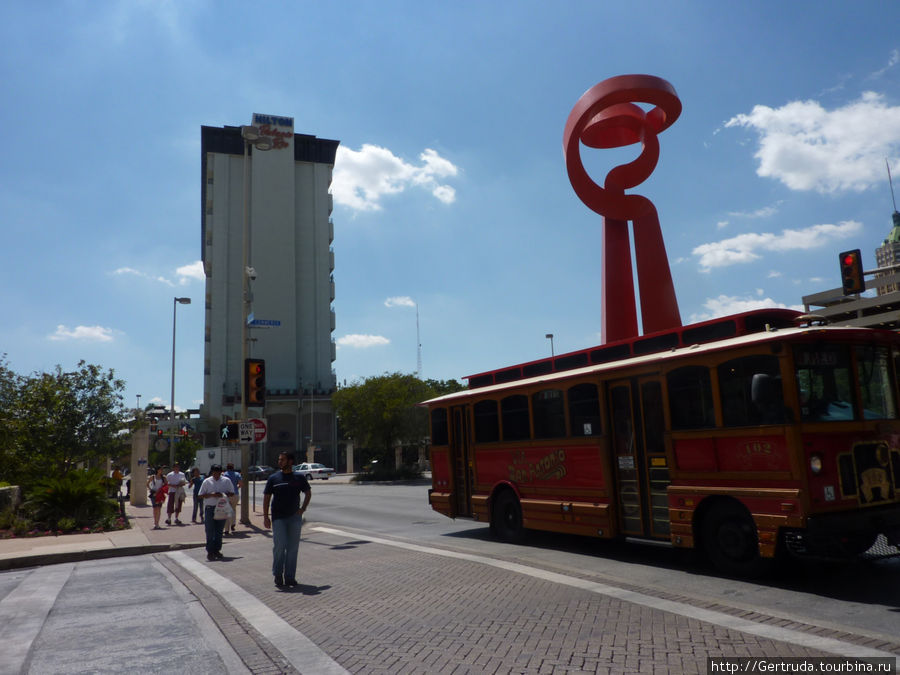 ГОродской экскурсионный автобус, за ним монумент Светоч дружбы Сан-Антонио, CША