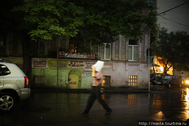 Прохожий, укрывающийся от дождя спешит домой. Тбилиси, Грузия