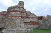Западная крепостная стена Несебра являлась частью укрепительной системы города. В настоящее время большая часть системы находится под водой. Длина сохранившегося участка стены достигает 100 м, а максимальная высота 8 м. Построена смешанной кладкой = опус микстум. Ранневизантийская стена (V—VI в.) следует трассе фракийской (VIII—VI в. до н. э.) и античной (IV—III в. до н. э.) крепостной стены. Северный и южный края стены находились в море, играя роль стен причалов для двух городских пристаней. Ворота, расположенные напротив перешейка, огорожены двумя пятиугольными башнями. В стороне от них были симметрично построены полукруглые и круглые башни. Две двери- опускающаяся и двухстворчатая — плотно закрывали основной вход в город. Документированы пять реконструкций стены в период с VII по XIX в. Основные раскопки и изучение сохранившихся частей крепостной стены велись с 1958 до 1969 г., после чего с 1970 до 1981 конcервировались и реставрировались.