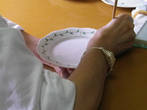 За первым столом девушка рисовала на тарелках растительный орнамент Петрушка.