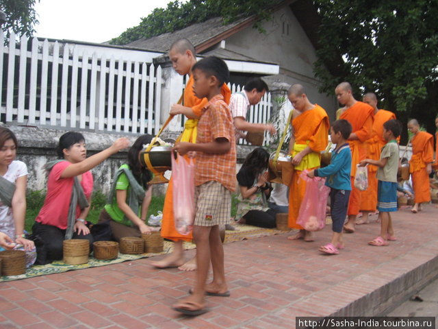 Рядом с монахами крутятся дети из бедных семей с большими пакетами
— им тоже перепадает милостыня, но уже из рук монахов,
так как обычно монахам жертвуют больше, чем они могут съесть. Луанг-Прабанг, Лаос