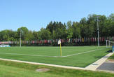Справа от помещения поле с искусственным газоном и флагами всех государств — членов ФИФА