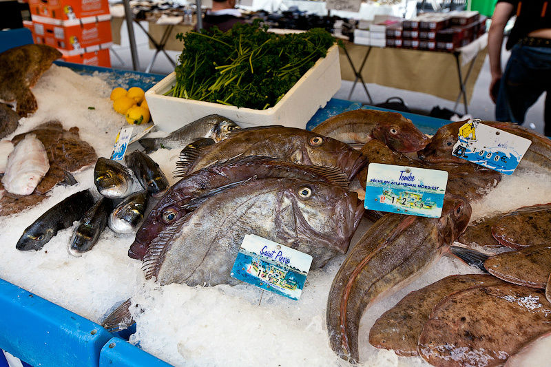 Рядом идут оживленные торги в уличных лавках: море рыбы Париж, Франция