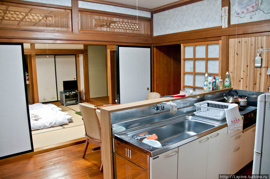 Внутренние помещения от входа: кухня, в глубине — жилая комната 8 татами с уже разложенными футонами. Сэнбоку, Япония