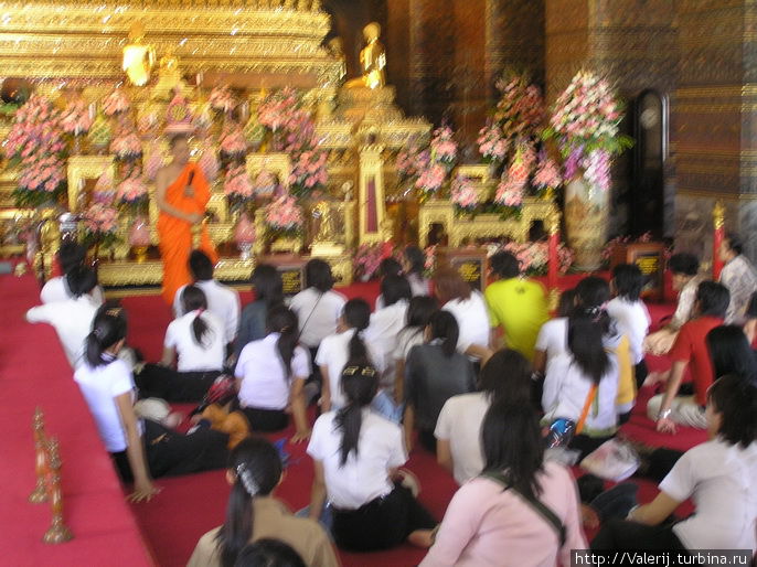 Урок, который монах ведет со школьниками у скульптуры Бронзового Будды в Главной часовне храма Ват По. Бангкок, Таиланд