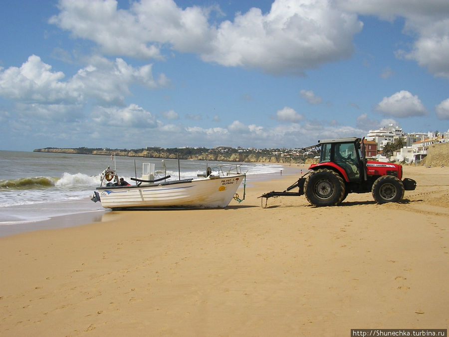 Полоса песка настолько широка, что рыбацкие лодки вытаскивают на берег специальные трактора. Регион Алгарве, Португалия
