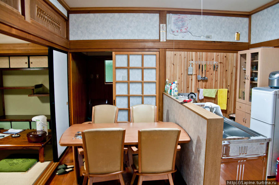 Кухня с обратной стороны, от входа в гостиную. В глубине — раздвижные двери в предбанник онсэнной. Сэнбоку, Япония