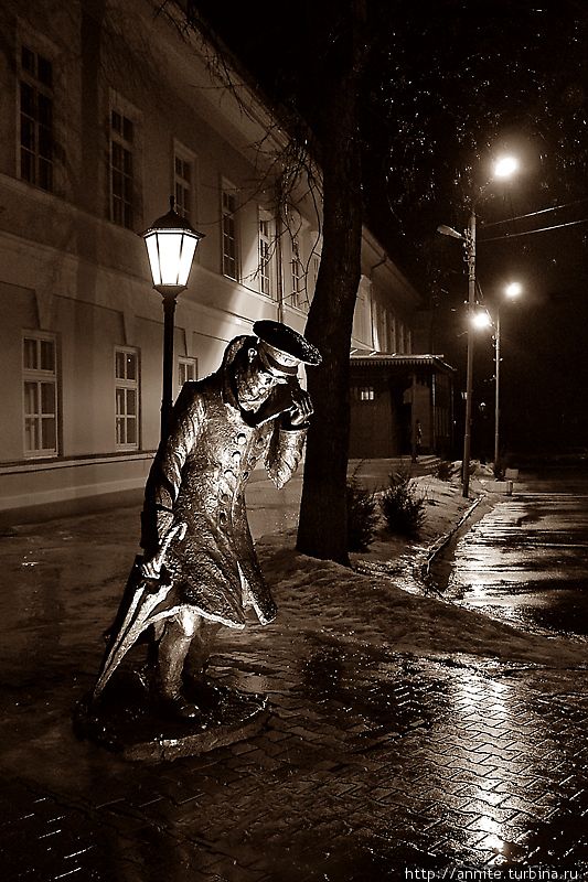 Беликов, пытающийся укрыться от дождя и мокрого снега, да и от самого себя, покидает гимназию поздним вечером. Фото не моё, нашла в интернете, уж очень оно характеризует скульптуру.
