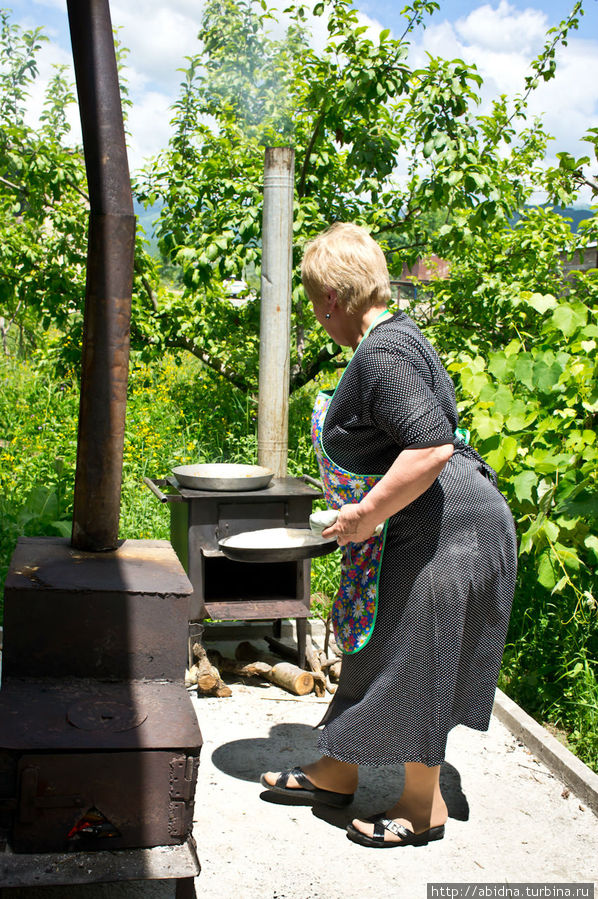 Третья женщина отправляет пироги в печь, достает готовые и смазывает их. Южная Осетия