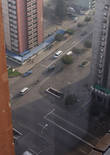 3. Самое потрясающее зрелище в Пхеньяне в семь утра, тем более после Пекина, это пустые улицы и строгие соблюдения правил движения. При всём неналичии другого транспорта, машины останавливаются  на красный свет светофора, мигают нужными поворотниками, скорость соблюдают наистрожайше. Хотя даже не это потрясает, а то как тщательно водители  стараются остановиться в рамках расчерченных белых линий, как аккуратно двигают с места и поворачивают.
Ещё больше чем поведение водителей, потрясает поведение пешехрдов. На этом  перекрёстке нет наземного перехода, есть подземный. Быстренько через улицу эдесь никто не перебегает, даже если что-то надо прямо напротив, а до перехода далеко. Здесь все дисциплинированно доходят до перехода, переходят на другую сторону и идут в продолжают путь в нужном направлении, даже если надо возвращаться обратно.
Низкая  пристройка под крышей — магазин, где время от времени наблюдались очереди.