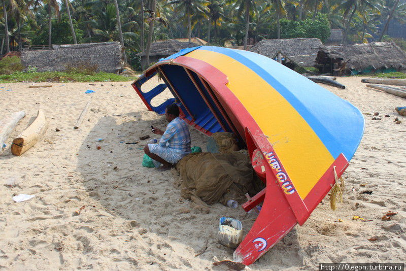 Рыбак спрятался в тени лодки Варкала, Индия