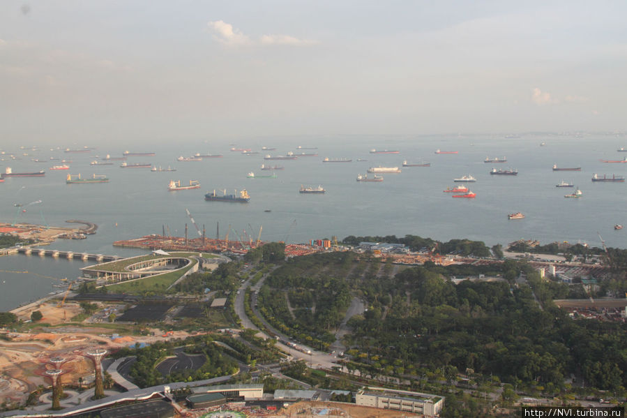 Вдали, сколько хватает обзора — суда, корабли на рейде в ожидании прохода через пролив. Сингапур (город-государство)