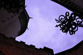 Силуэты кованых розеток причудливо изящны в высоком замковом дворе-колодце на фоне вечернего неба