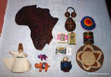 Фото 2. Тут у нас: деревянная карта Африки, войлочная фигурка дервиша, две фигурки бегемотиков, танцевальная принадлежность и сосуд для воды из тыквообразного плода, два кусочка натурального мыла, магнитик, войлочная фигурка бабушки, еврейская кипа, баночка растворимого кофе, плетеная тарелка.