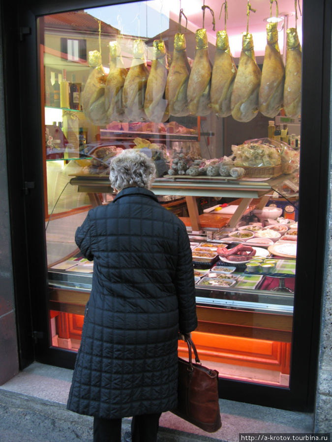 Бабуля смотрит на витрину с мясом и сосисками Саронно, Италия