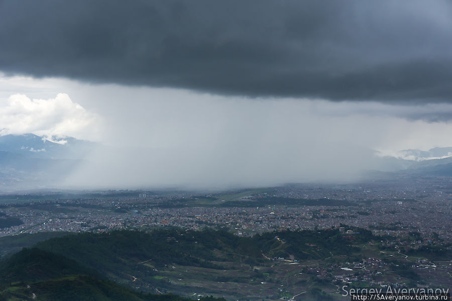 Дождь накрывает город. В аэропорту виден выруливающий на взлётную полосу самолёт. Катманду, Непал