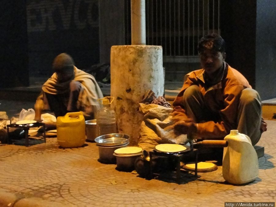 Рикши готовят ужин. Их подстилки и вещи днём всегда аккуратно сложены в углу здания. Чандигарх, Индия