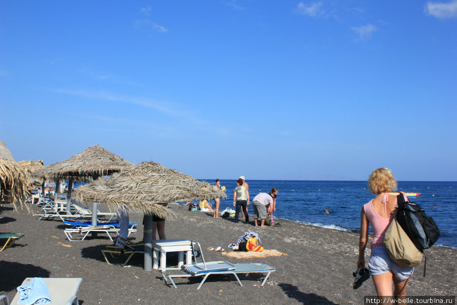 Пляж Камари знаменит черным вулканическим песком и кристально чистым морем. Остров Санторини, Греция