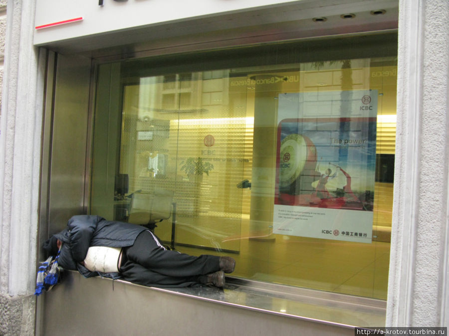 Человек спит в окне банка, вероятно ждёт открытия банка (воскресенье) Милан, Италия
