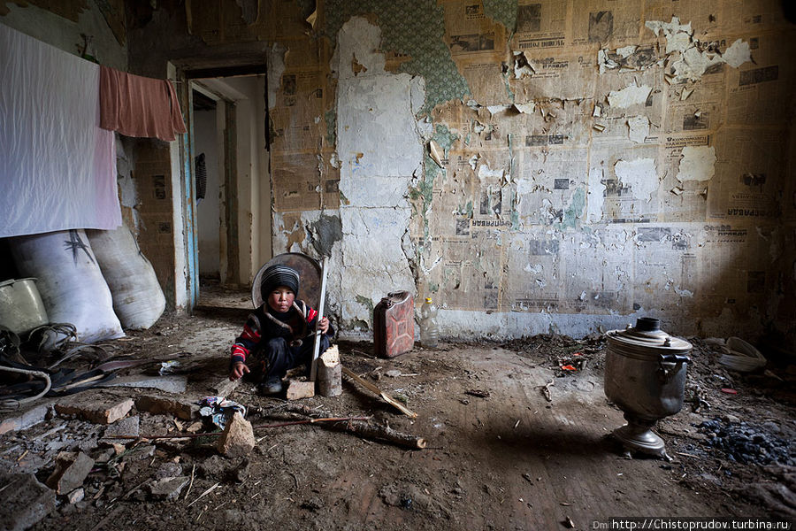 Ребенок играет с палкой, бревном и расколотым кирпичем в летнем домике чабанов. Киргизия