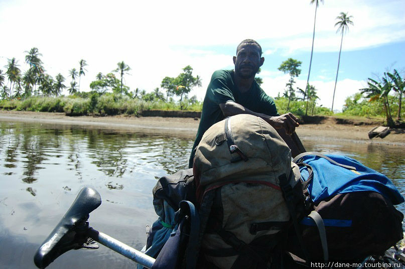 Папуас помогает пересечь глубокую реку на каноэ Папуа-Новая Гвинея