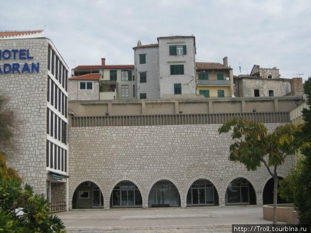 Удивительно сочетание старинной по виду стены и совершенно нового, под ее фактуру замаскированного здания Шибеник, Хорватия