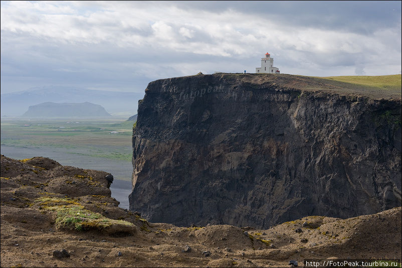 На вершине скалы находится маяк, стоически перенося все океанские шторма и ветра. Южная Исландия, Исландия