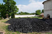 На заднем дворе насыпана большая куча угля, видимо для отопления зимой.