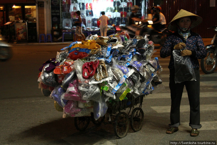 Продавщица всякой всячина на ночном базаре в квартале ремесленников Ханой, Вьетнам