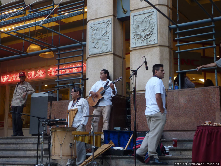 Музыканты играют и днем и вечером на небольшой площадке у Riverwalk, на выходе из фудкорта Сан-Антонио, CША
