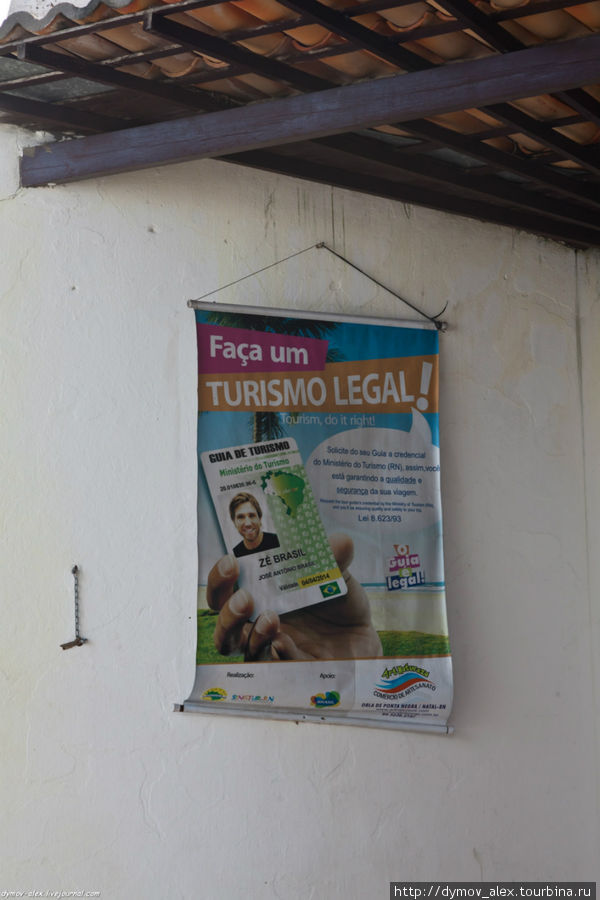 Надпись Делайте легальный туризм. Смешно, так как карточка белого гида, а протягивает ее, как видно по руке, черный. Натал, Бразилия