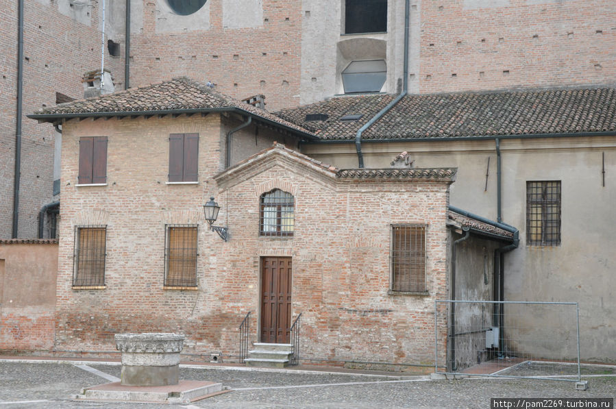 Притулившиеся домики к стене базилики Мантуя, Италия