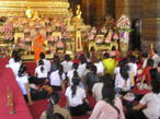 Урок, который монах ведет со школьниками у скульптуры Бронзового Будды в Главной часовне храма Ват По.