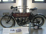 Phänomen red 1905
Велосипедная фабрика «Phanomen», основанная еще в 1888 году, свой первый мотоцикл изготовила в начале XX века. Типичные для своего времени мотоциклы оснащались одно- и двухцилиндровыми V-образными двигателями «Фафнир» с автоматическим впускным клапаном. Привод заднего колеса был ременным. С1907 года в серию пошли трехколесные мотоциклы в пассажирском и грузовом вариантах, а к 1910 году автомобили полностью вытеснили двухколесную технику из производственной программы.

Чистокровный «немец» — мотоцикл Phanomen 1905 года. 500-кубовая «двойка» Fafnir мощностью около 2 л.с. разгоняла машину до скорости 75 км/ч. Для освещения служил ацетиленовый фонарь, газ для него вырабатывался в «генераторе» позади фары. Обратите внимание на обилие рычажков на бензобаке — на них выведено управление и карбюратором, и зажиганием.