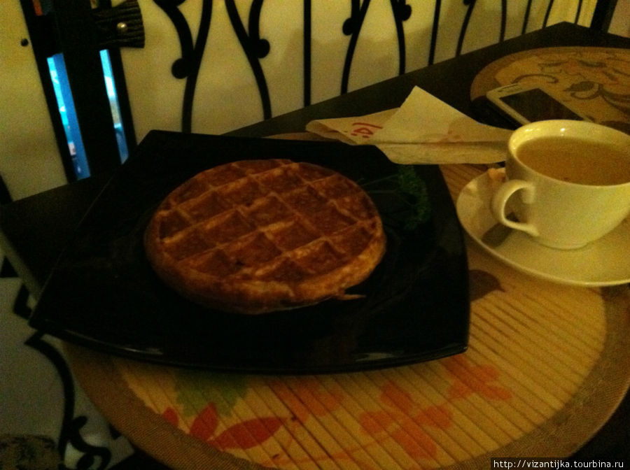 Льёжская вафля на чёрной тарелочке с чашечкой кофе.