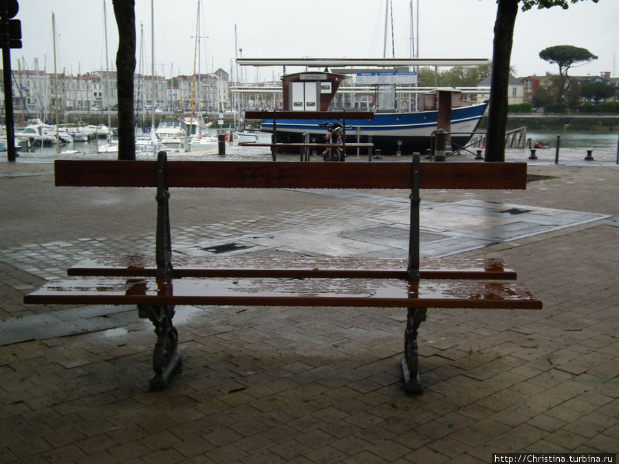 Одинокая мокрая скамейка на набережной Ля-Рошель, Франция