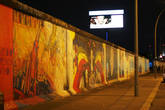 Как выяснилось, на остатках берлинской стены не оригинальные рисунки. Они были нарисованы по-новому хотя и теми же авторами.
Дело в том, что за двадцать лет краски на бетонных блоках поблекли, контуры многих изображений стерлись. Туристы писали на стенах свои имена и даты визита в Германию, откалывали куски бетона «на память». Из-за этого во многих местах стены обнажилась и успела проржаветь арматура, а иные рисунки, как, например, знаменитый «Братский поцелуй» Брежнева и Хонеккера — картину российского художника Дмитрия Врубеля — под слоем посторонних надписей узнать можно было с большим трудом.