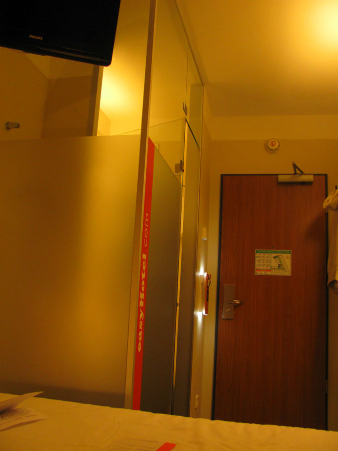 Гостиничный номер: небольшой коридор, санузел за матовым стеклом и кровать.