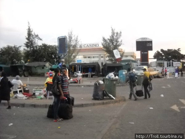 Африканские контрасты: кучи мусора и уличные торговцы на фоне Казино Габороне, Ботсвана