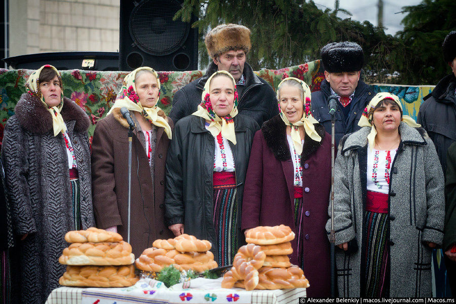 С десяток бабушек в одинаковых платках стоят перед столом с какими-то бубликами и поют заунывную грустную песню на румынском языке. За ними — плакаты с дедом Морозом и пожелания счастливого нового года. Но почему же песня такая грустная? Кишинёв, Молдова