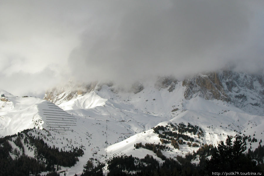 За облаками Sassolungo, 3181 м. Лыжников сюда поднимают из Campitello. Валь-ди-Фасса, Италия