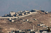 Та самая заградительная стена, которую Израиль начал строить для отгорождения Израиля от Западного берега реки Иордан в 2003 году и строит до сих пор, чтобы защититься от нападений палестинцев и которая вызывала много споров, в частности из-за того что Израиль отошел от т.н. зеленой линии, по которой проходит граница.
Общая длинна более 700км, 10% представляет собой бетонную стену как на снимке, остальное забор с колючкой с 60 метровой зоной отчуждения — на Берлинскую стену смахивает.
По статистике после строительства количество терактов и нападений снизилось.