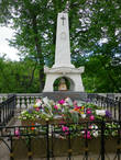 Обилие живых цветов на белом мраморе памятника