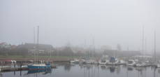 Туманный вид на Истад с пирса яхт-клуба.