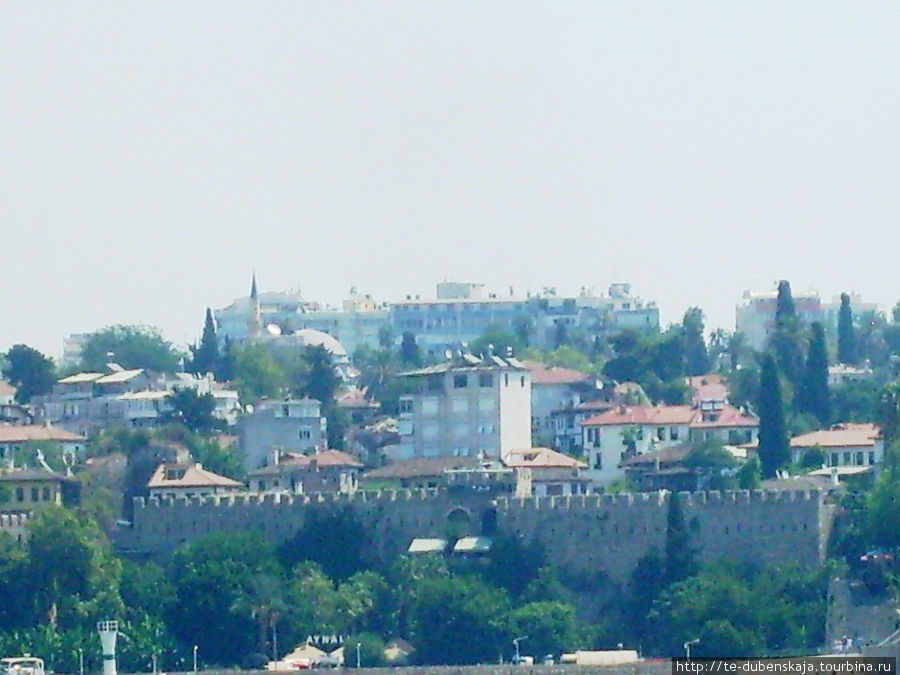 Стены старой крепости хорошо выделяются на фоне высоких отелей. Кемер, Турция