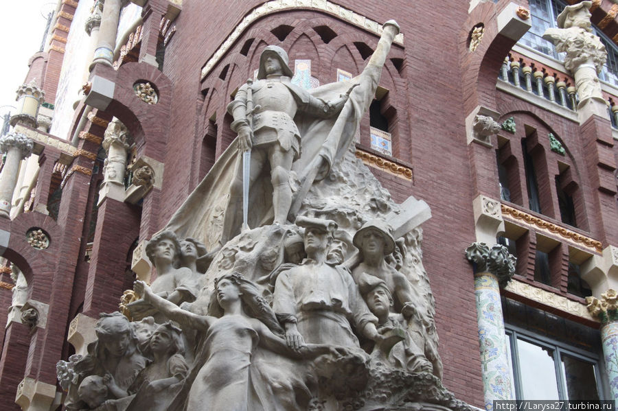 На углу фасада — скульптурная группа, посвящённая героям народных песен Каталонии. Скульптор Мигель Блай. Барселона, Испания