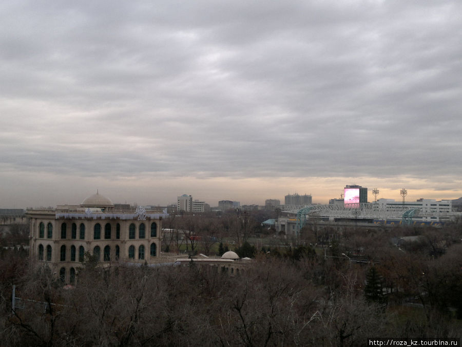 на горизонте, за Центральным стадионом — самый большой в Алматы экран с рекламой Алматы, Казахстан