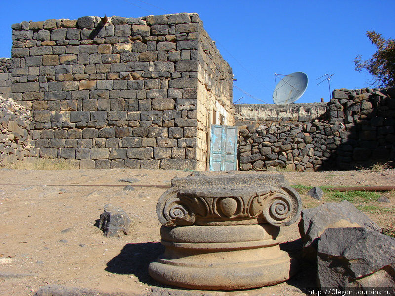 У входов в дома лежат элементы древних зданий Босра, Сирия