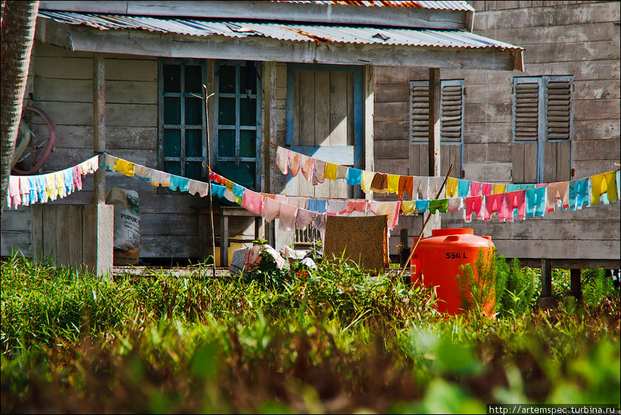 Вокруг сушатся бесчисленные детские вещи. Рядом стоит бак для питьевой воды — на островах ее источников нет. Суматра, Индонезия