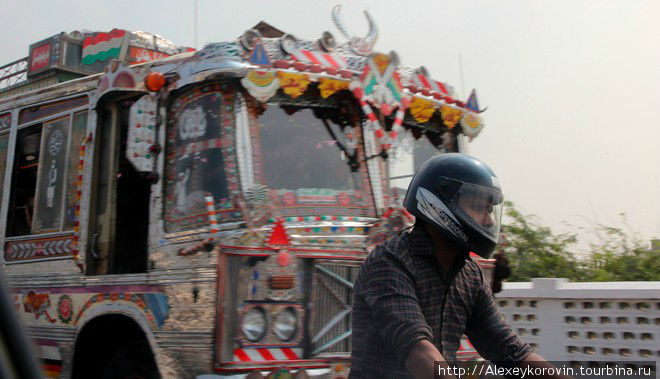 Атрибуты Пакистана: разрисованный автобус и мотоциклист Карачи, Пакистан